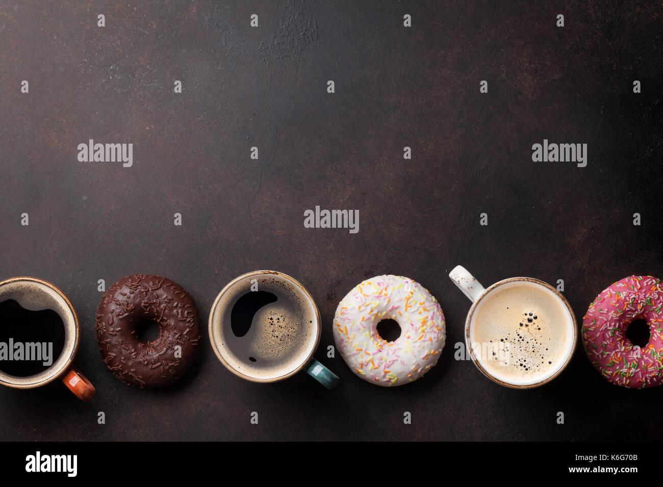 Coffee cups and colorful donuts on stone table. Top view with copy ...