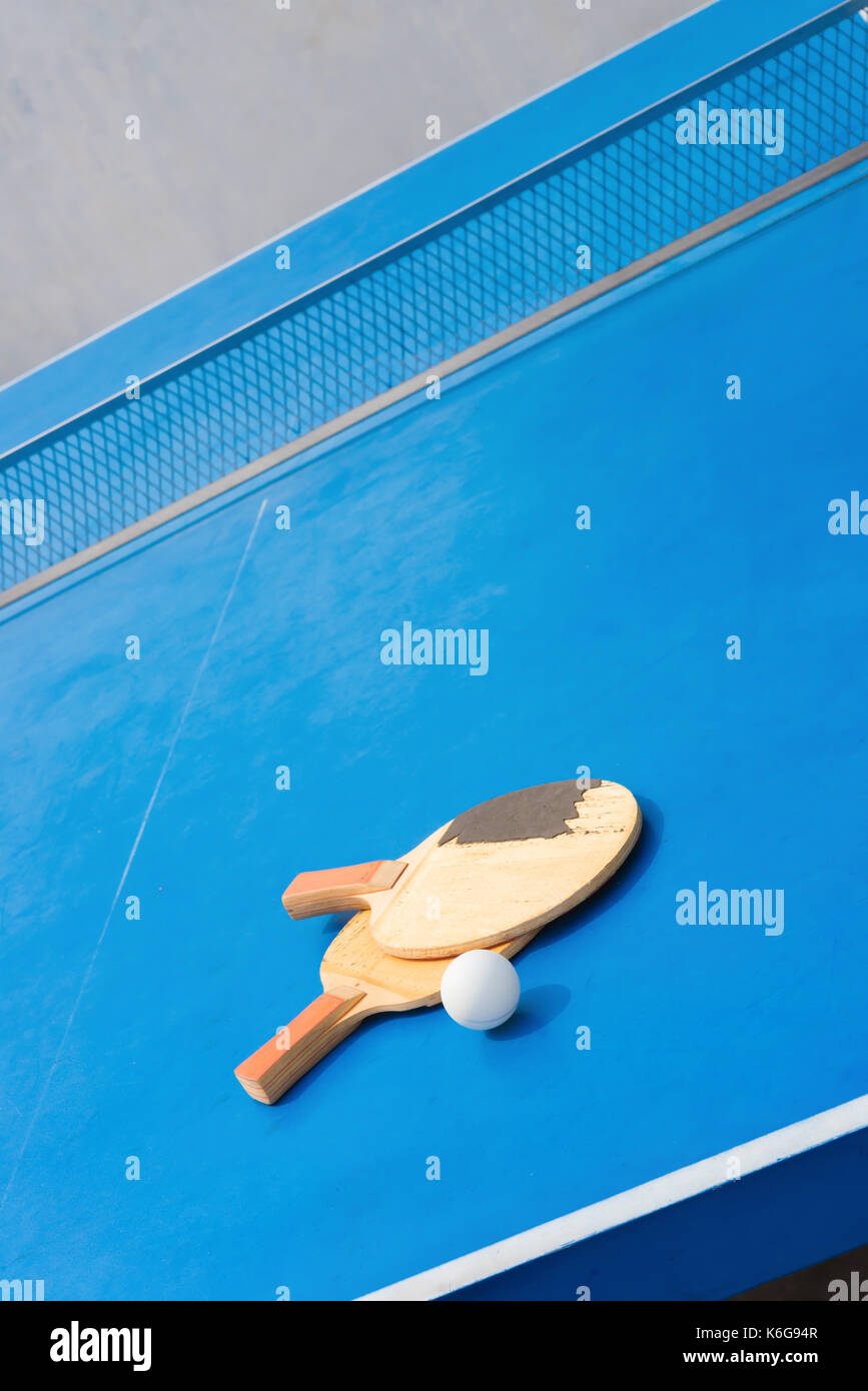old pingpong rackets and ball and net on a blue pingpong table Stock Photo