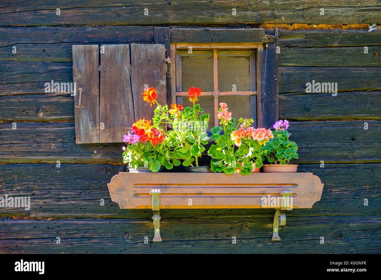 The small window of an old wooden farmhouse, decorated with colorful ...