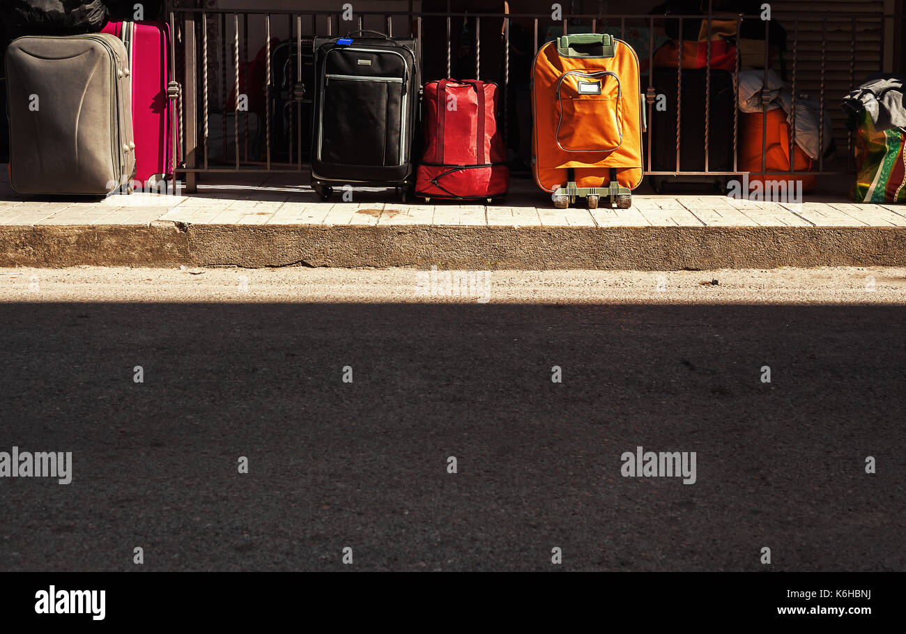 Details of various travel bags on sidewalk, part of street asphalt in foreground. Stock Photo