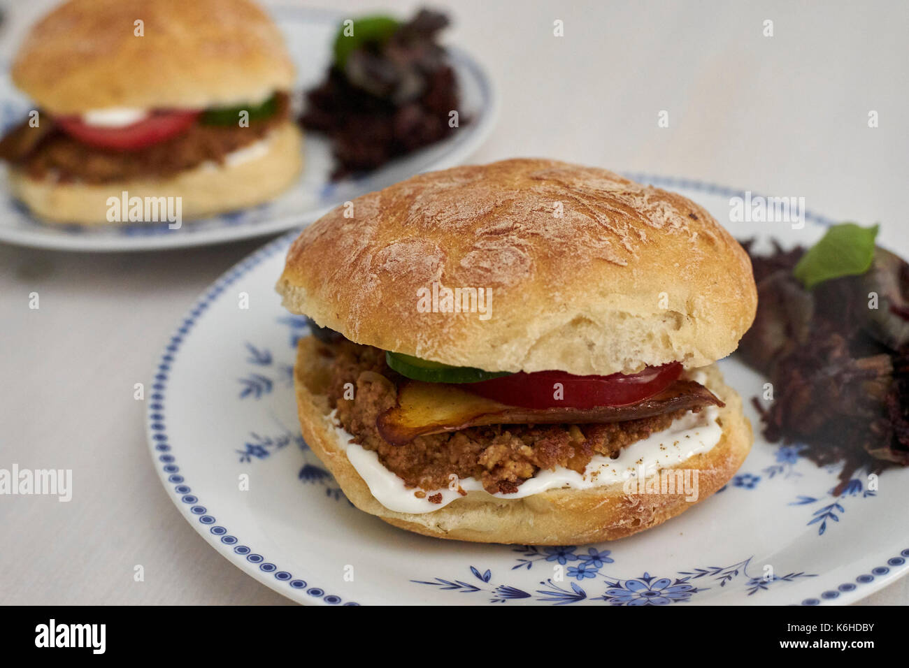 Two vegan burgers with paprika and tofu on plates Stock Photo