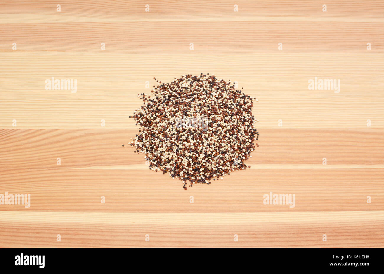 Mixed red, white and black quinoa on a wooden background, pine wood grain Stock Photo