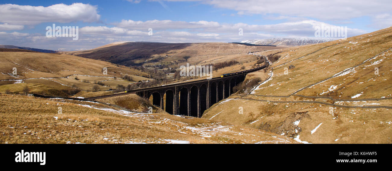 A Class 66 diesel locomotive hauls a train of freight wagons across Arten Gill Viaduct on moorland above Dentdale in England's Yorkshire Dales Nationa Stock Photo