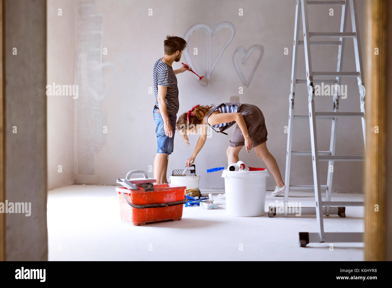 Couple painting hearts on the wall in their house. Stock Photo