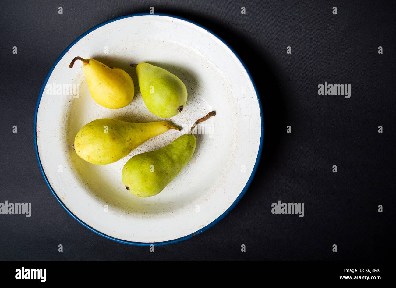 Green pears in a plate on  black background Stock Photo