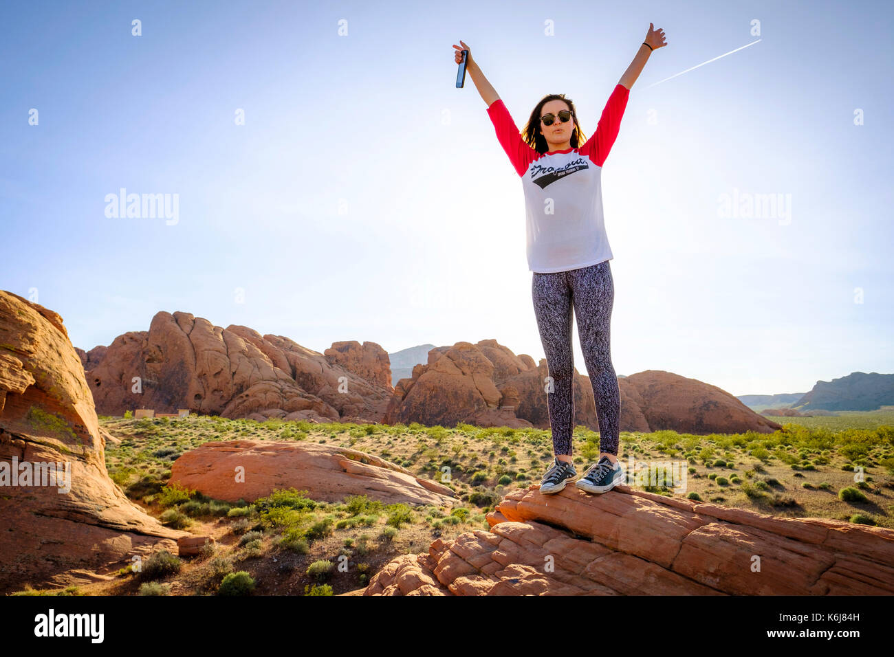 Woman standing in celebratory pose, Valley of Fire State Park, Nevada, USA Stock Photo