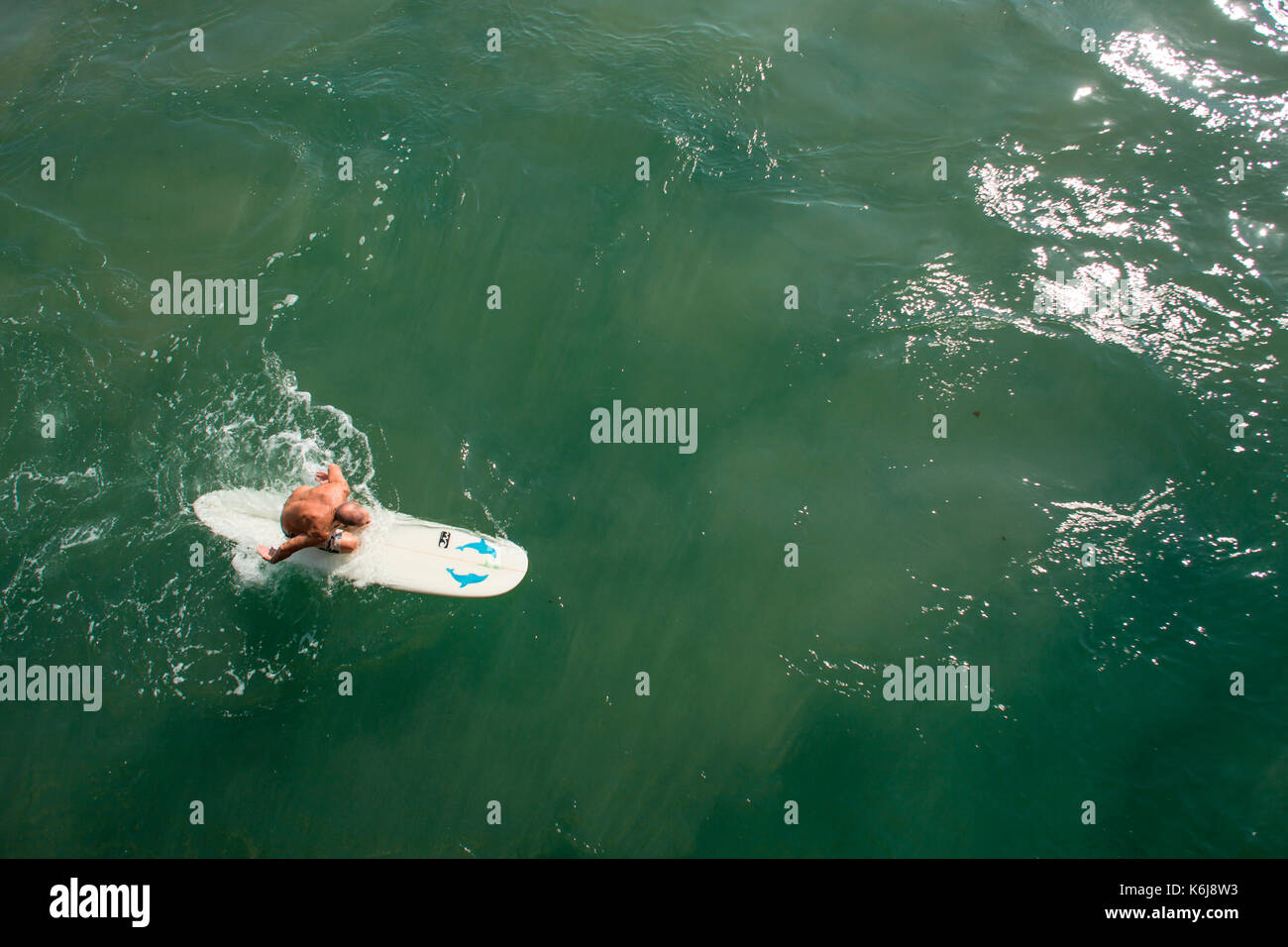 Senior man paddling surfboard next to pier near promenade on Golden Mile, Durban, South Africa Stock Photo