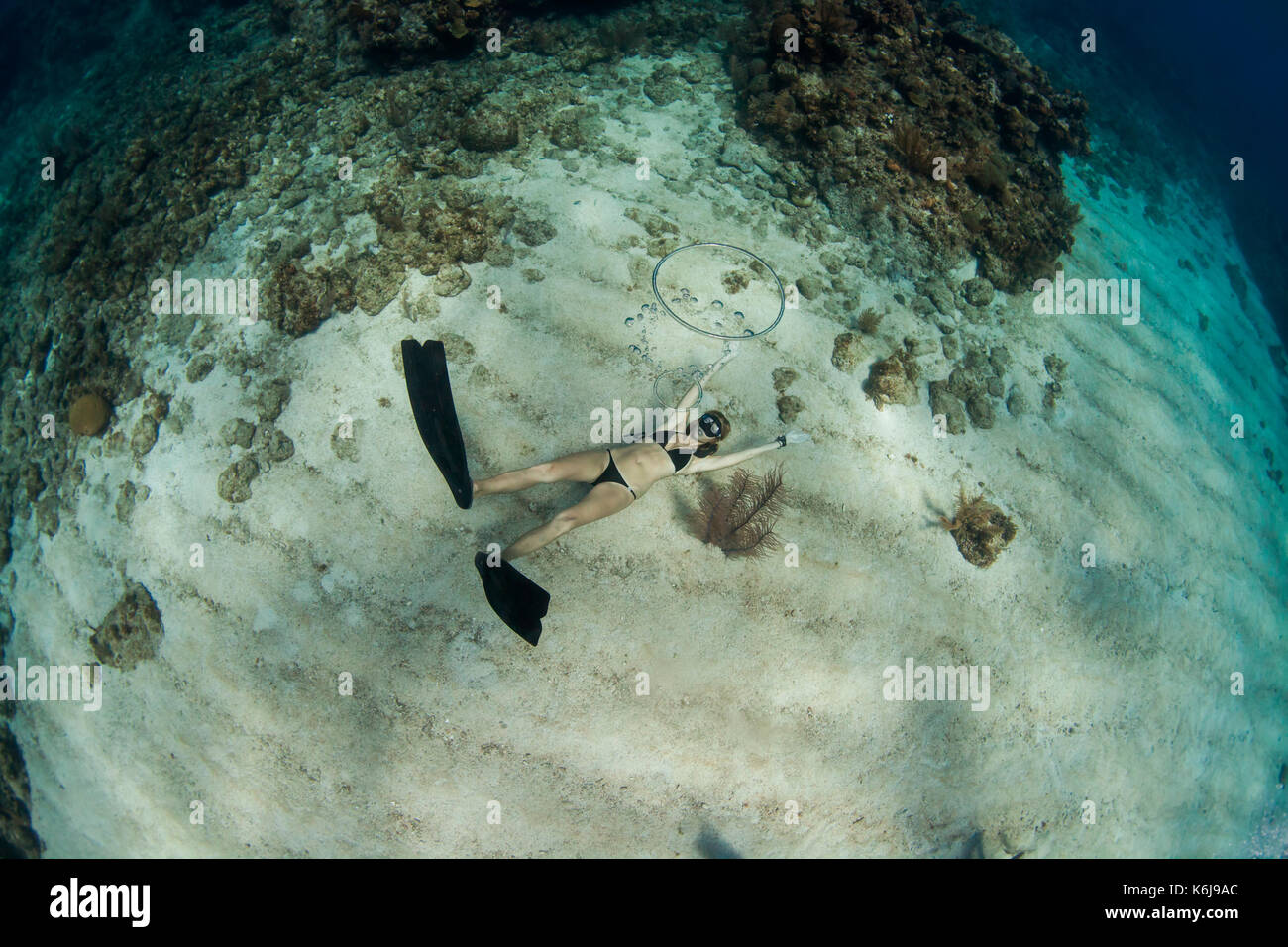 Woman blowing ring bubbles, freediving underwater off coast of Roatan