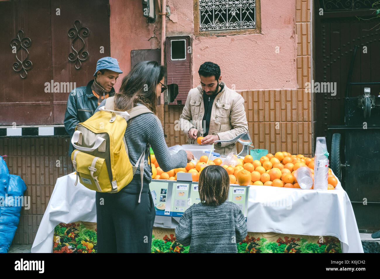Mother with son buying fresh orange juice in street market, Medina, Marrakesh, Morocco Stock Photo