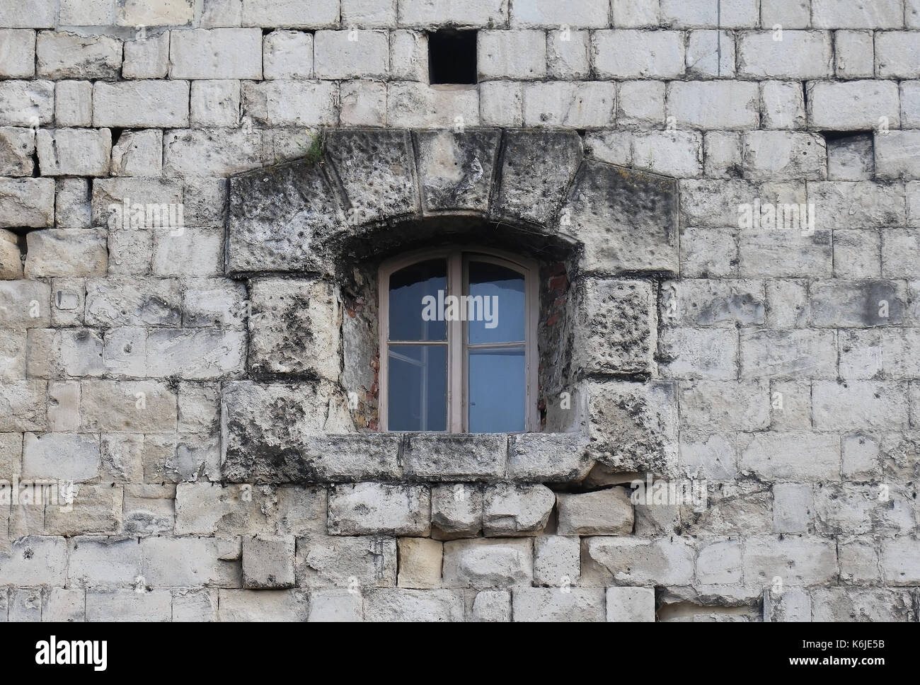 Small closed window on old stone building facade Stock Photo