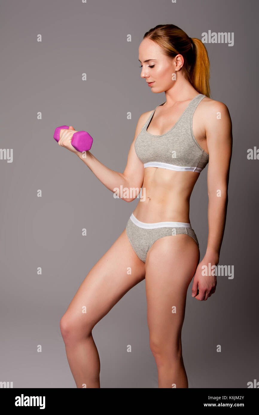 Beautiful athletic woman lifting weight dumbbell fitness workout. Stock Photo
