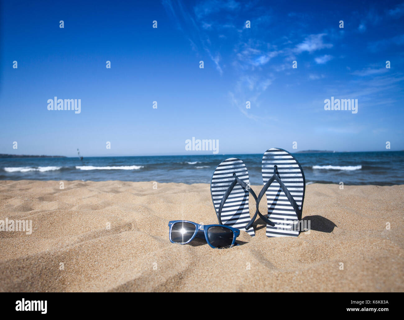 Blue sandal flip flop and sunglasses on the sand beach with blue sea ...