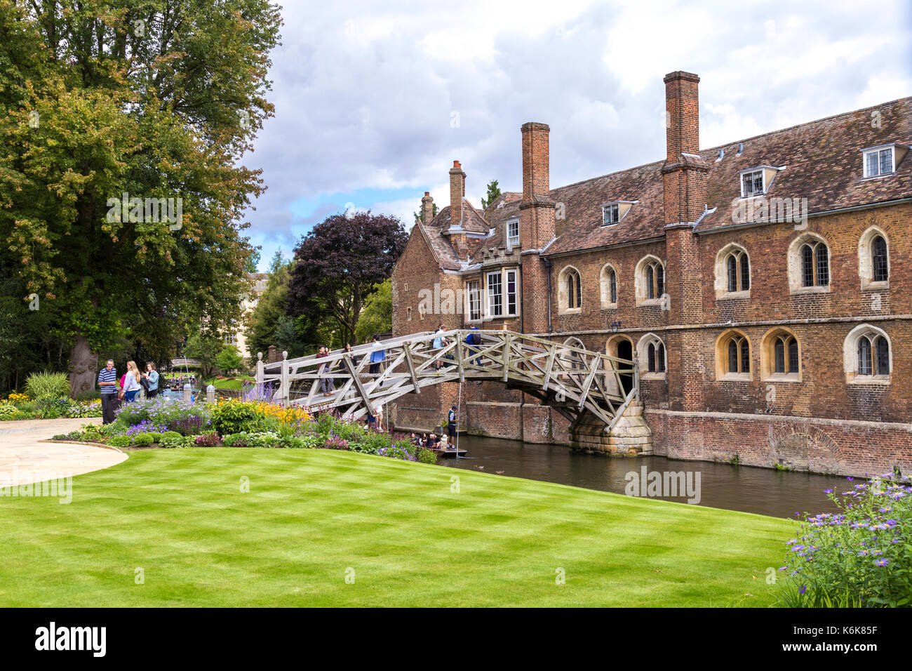 Mathematical Bridge and people punting on the Cam river, Queen's College building, Cambridge, UK Stock Photo