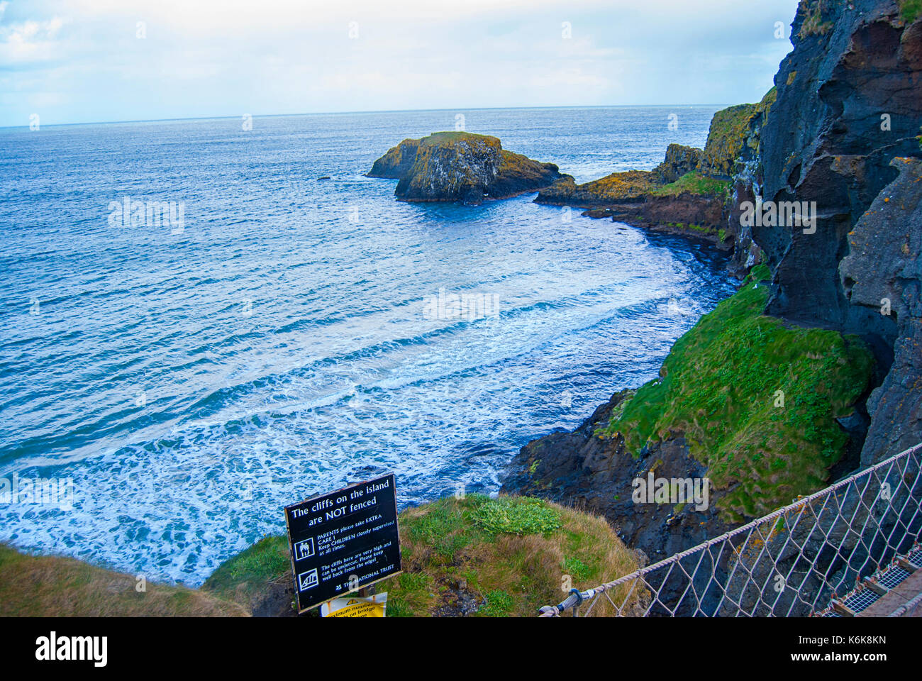Ballintoy, United Kingdom - May 2, 2016: Carrick-a-Rede Rope Bridge, a popular tourist destination in Northern Ireland. Tourists passing the bridge. Stock Photo