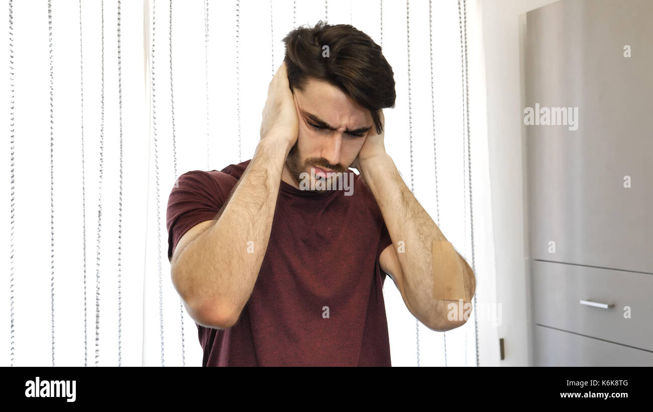 Young man covering his ears, too much noise Stock Photo