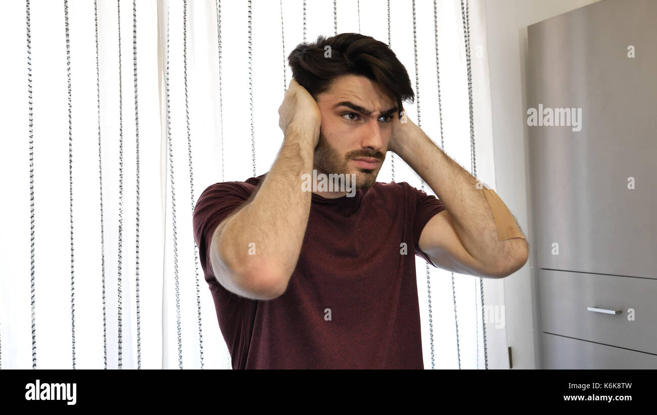 Young man covering his ears, too much noise Stock Photo