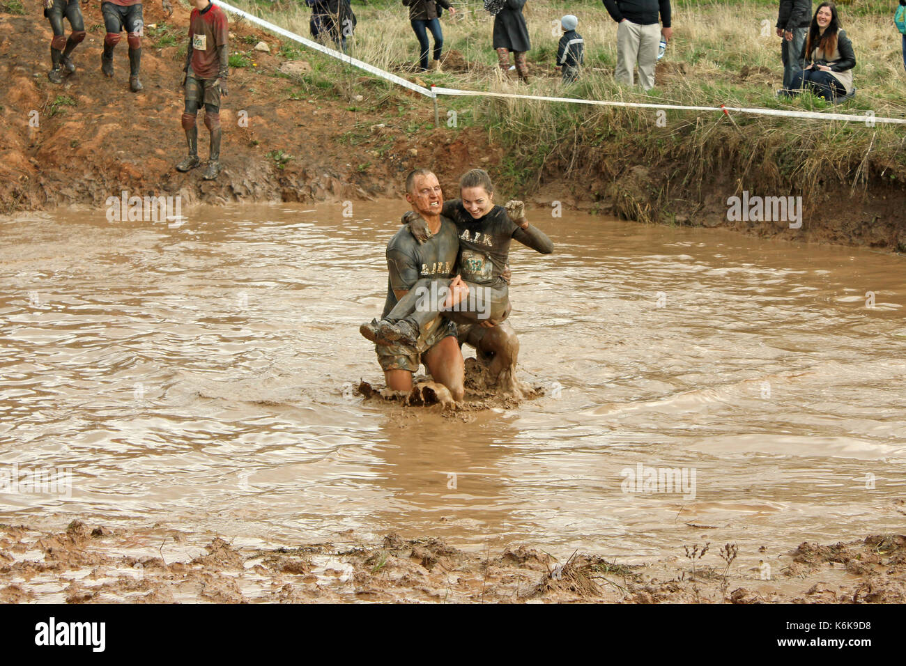 Cinevilla, Latvia - May 4th, 2014: Participants of the strong race 2014. A man carrying a woman through the mud - teamwork Stock Photo