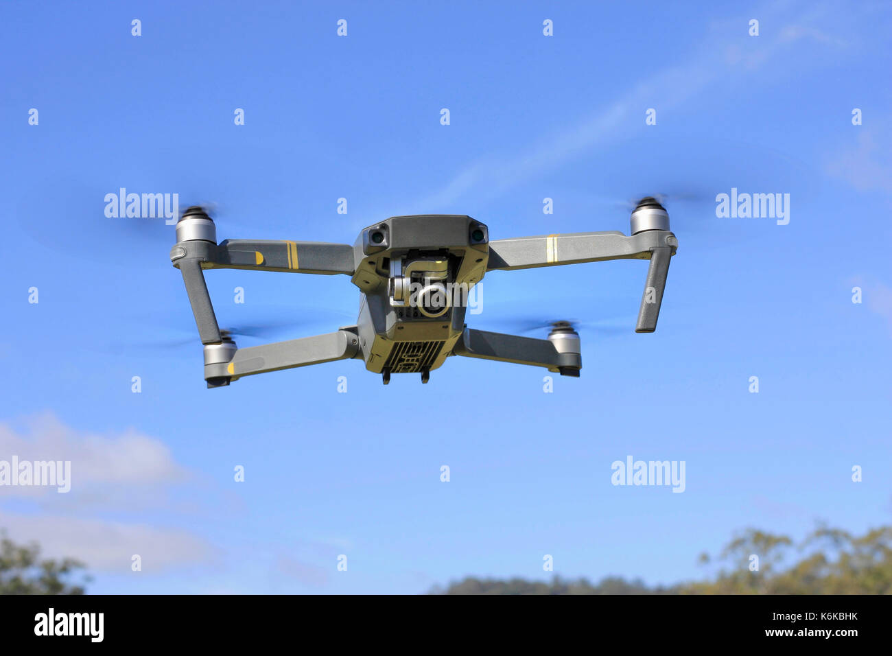 Drone quadcopter with digital camera in flight with blue sky Stock Photo
