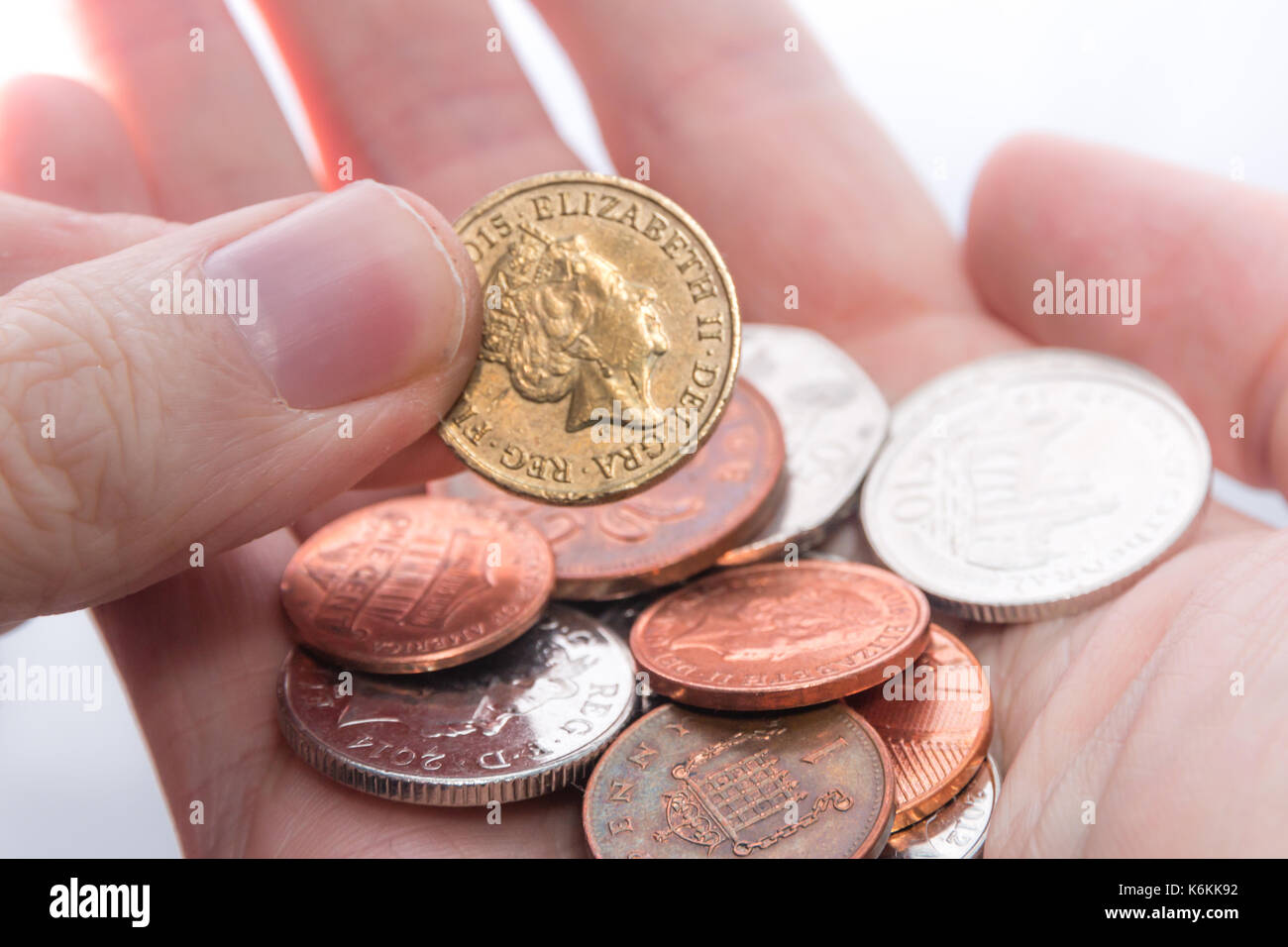 An old 2015 pound coin being picked up from a handful of assorted coins Stock Photo