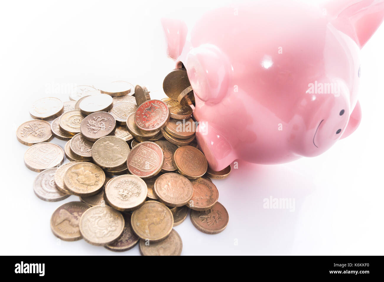 A pile of old pound coins falling out a piggy bank. Stock Photo