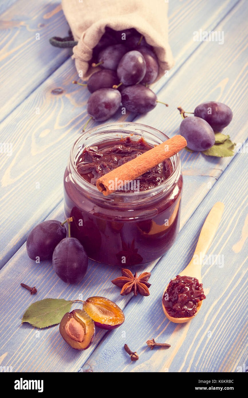 Vintage photo, Fresh plum jam or marmalade in glass jar, ripe fruits and spices on boards, concept of healthy sweet dessert Stock Photo