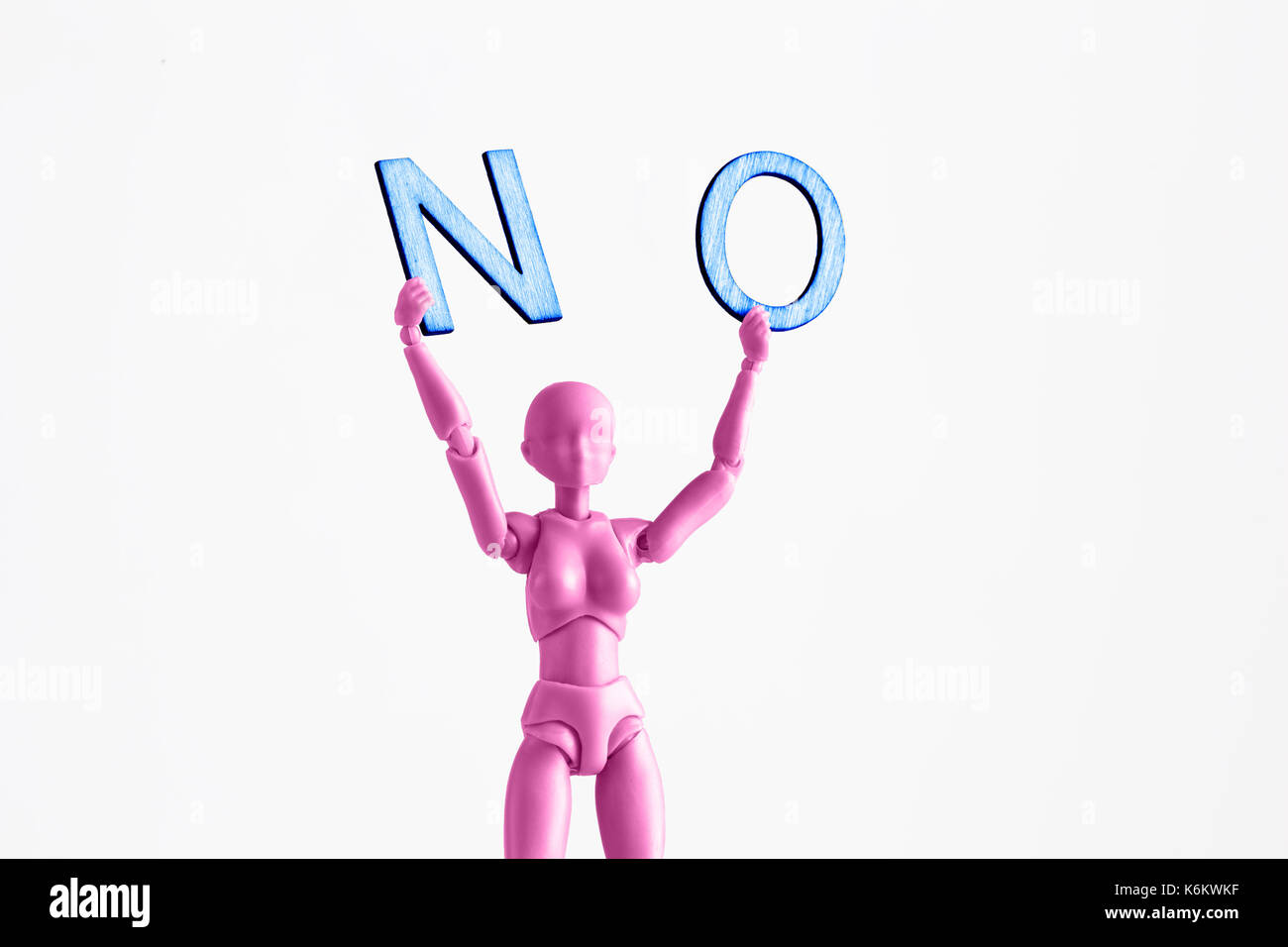 Pink female figurine closeup holding up the word NO. Isolated on white with copy space Stock Photo