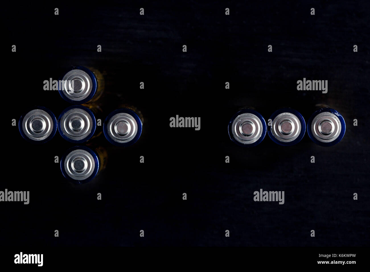 Plus and minus signs made of used AA batteries isolated on black with