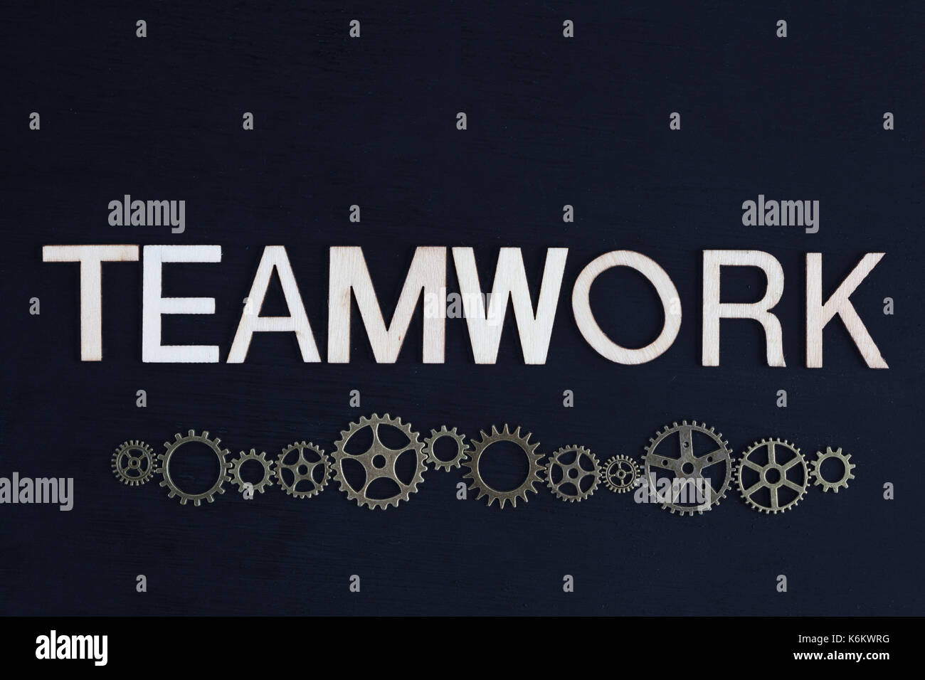 Concept of team work depicted with letters and cog wheels on dark background with copy space Stock Photo