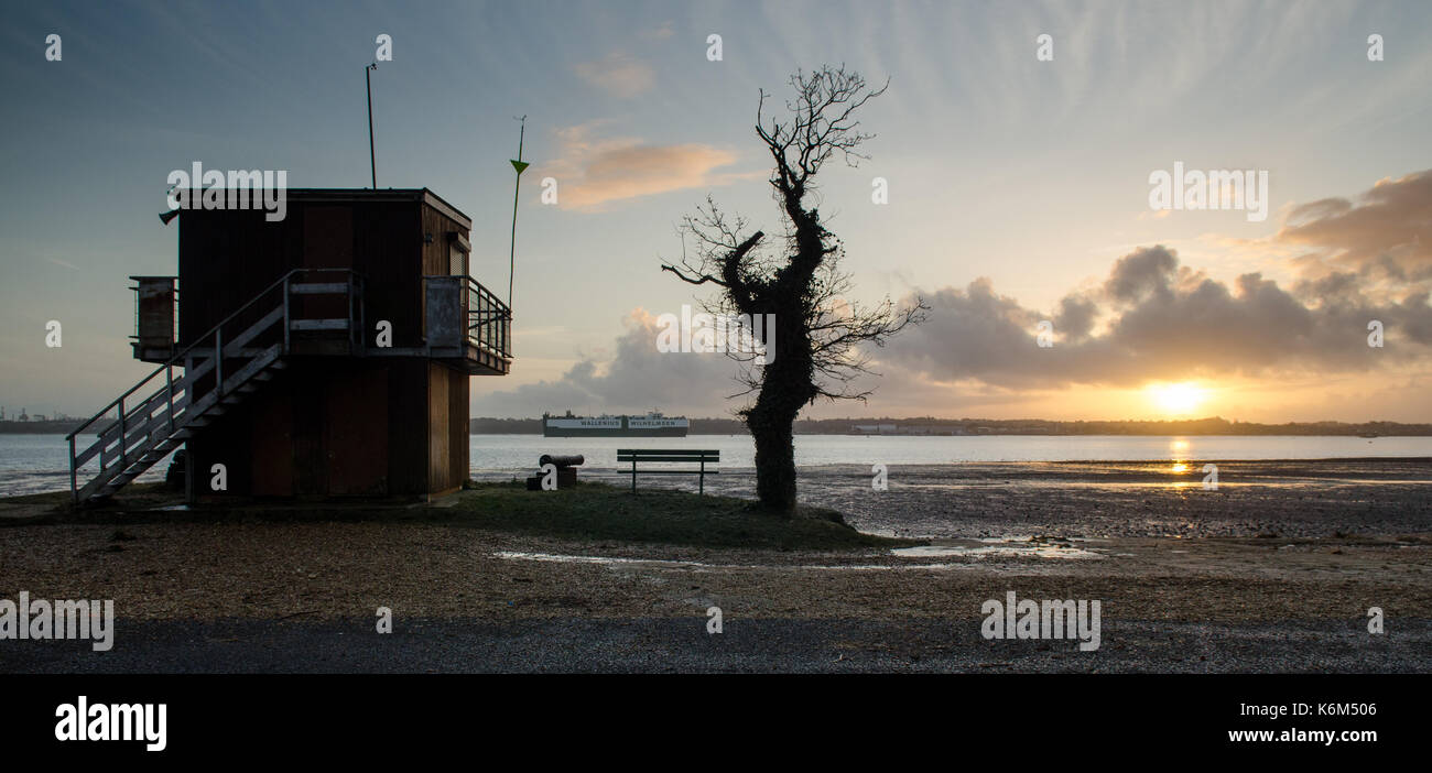 Southampton, England - February 16, 2014: A cargo ship enters Southampton Docks, seen from Weston Shore at sunset. Stock Photo