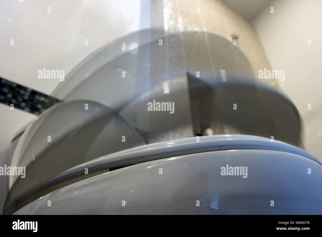 The toilet seat with lid moving down. The toilet bowl cover fall down