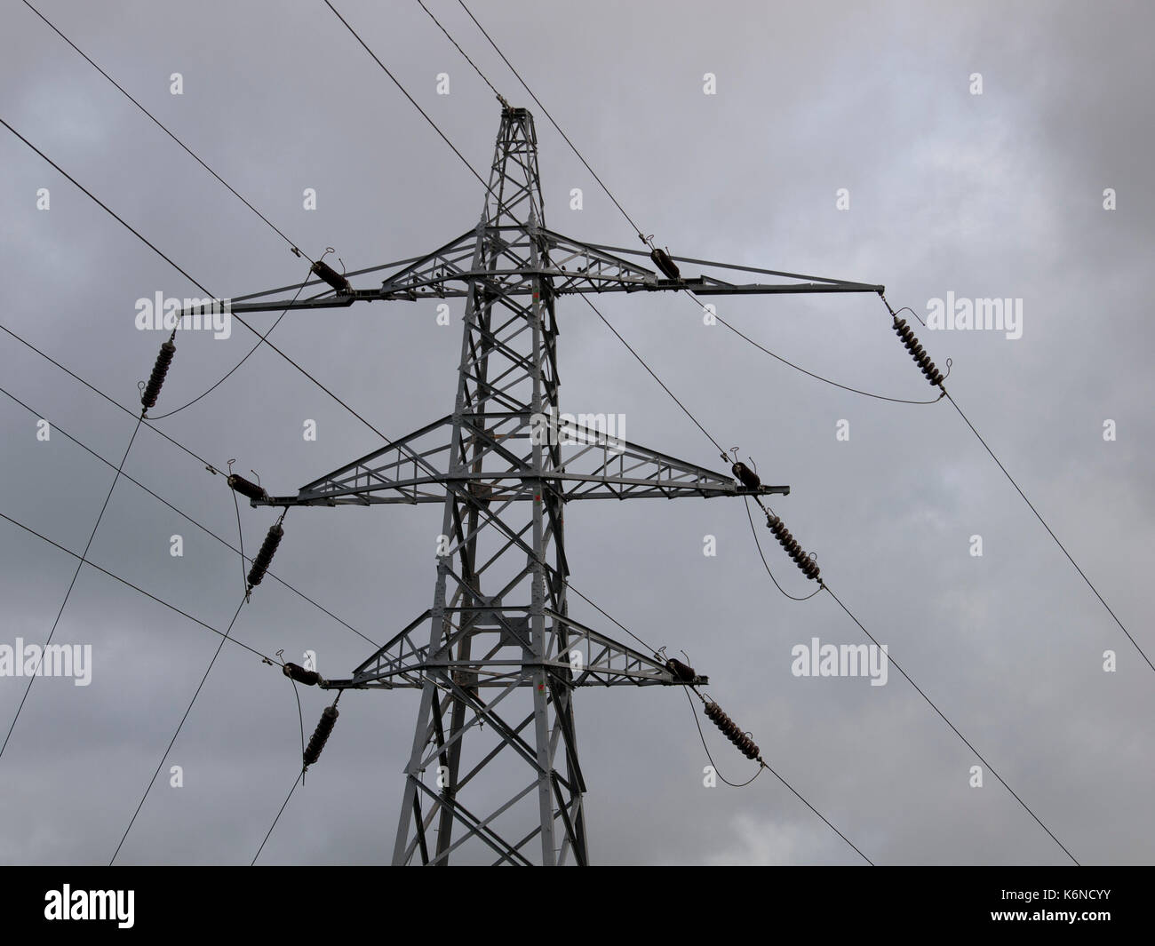 Electricity Pylon set against a grey cloudy sky Stock Photo - Alamy
