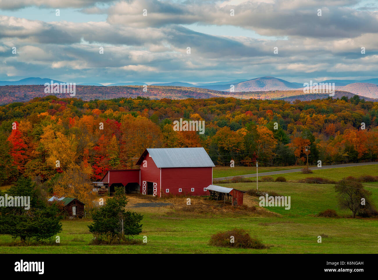 Hudson Valley NY Fall Colors - Red Barn and farmhouse with the warm and bright colors of peak fall foliage as a backdrop. The Shawangunk Ridge, also known as the Shawangunk Mountains or The Gunks, is a ridge of bedrock in Ulster County, Sullivan County and Orange County in the state of New York and can also be seen in the background. Stock Photo
