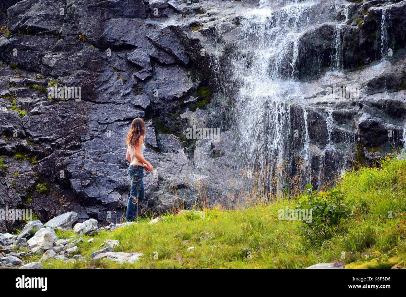 Hjorundfjord, Norway - October 2nd, 2017: Girl hiking to a Waterfall in Sunmore Alps, near Hjorundfjord, Norway Stock Photo