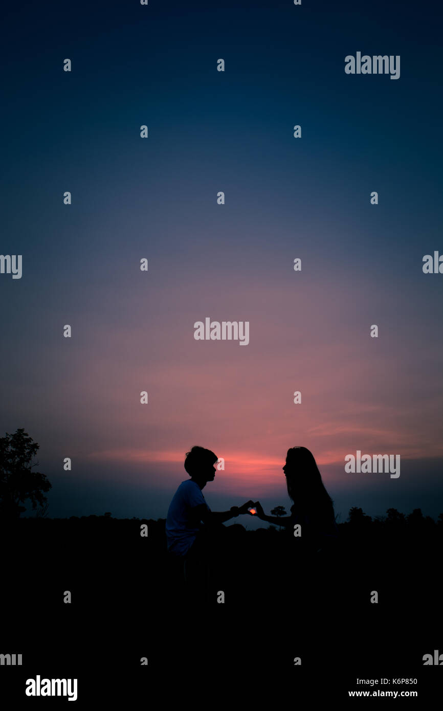 silhouette-of-a-couple-sitting-at-the-time-of-sunset-holding-hands