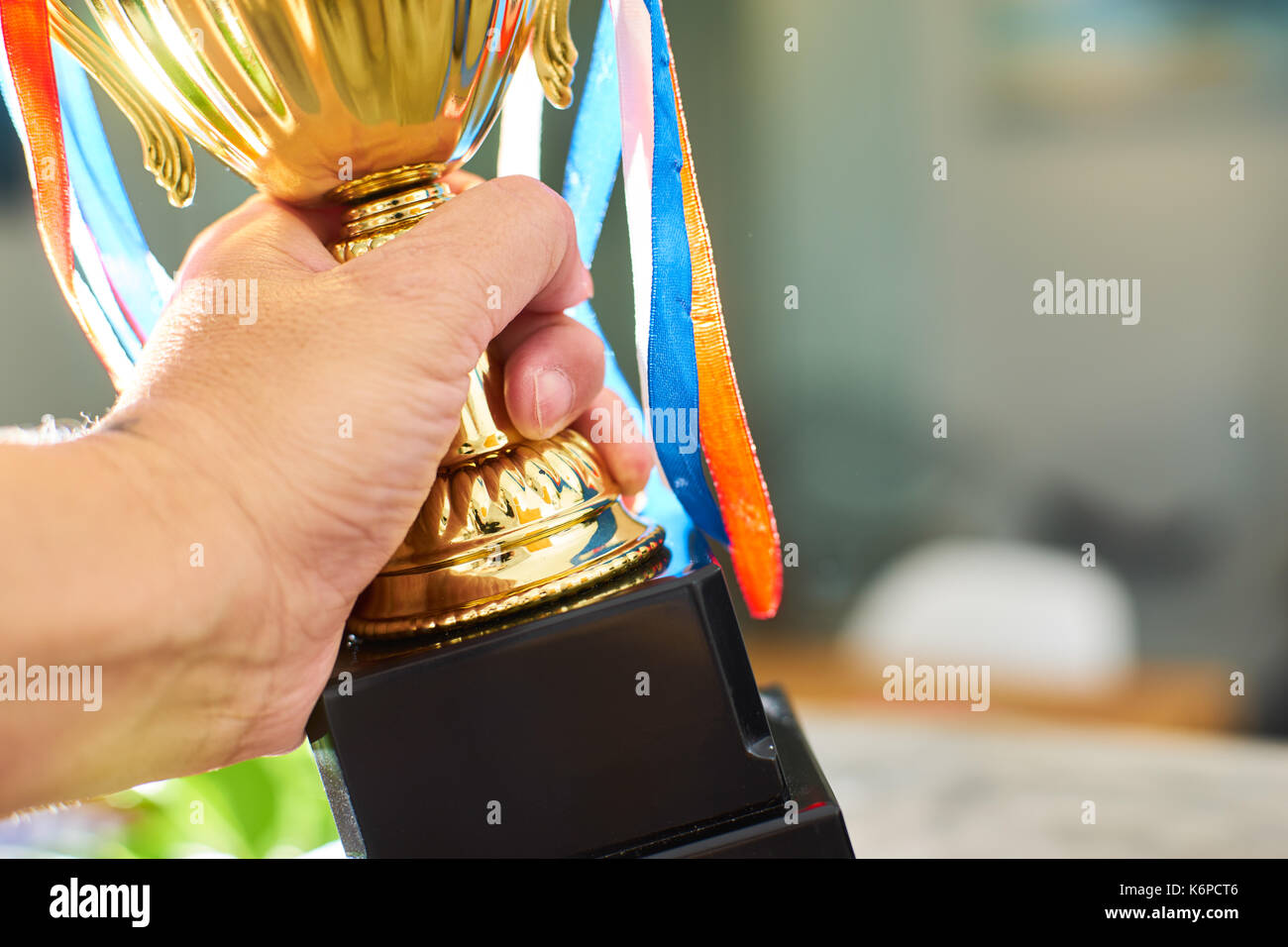 Young athlete holding up a gold trophy cup with space ready for your