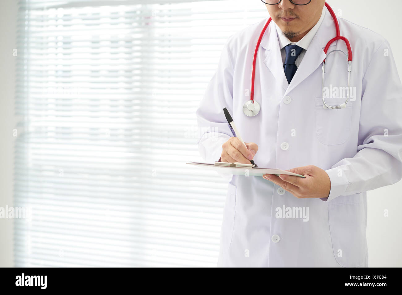 Doctor with a stethoscope and taking notes with bright background . Stock Photo