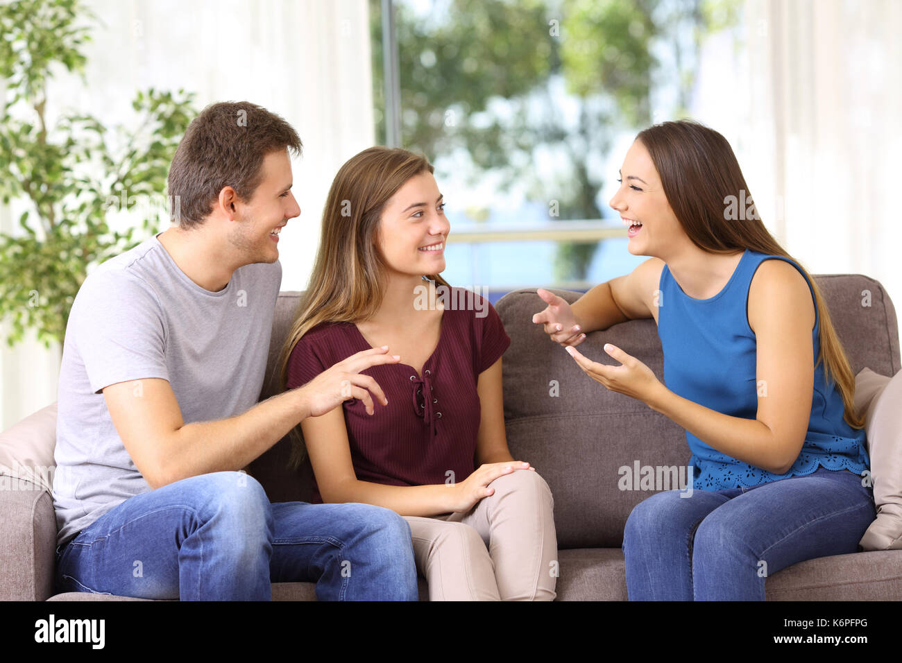 Three joyful friends talking sitting on a sofa at home Stock Photo - Alamy