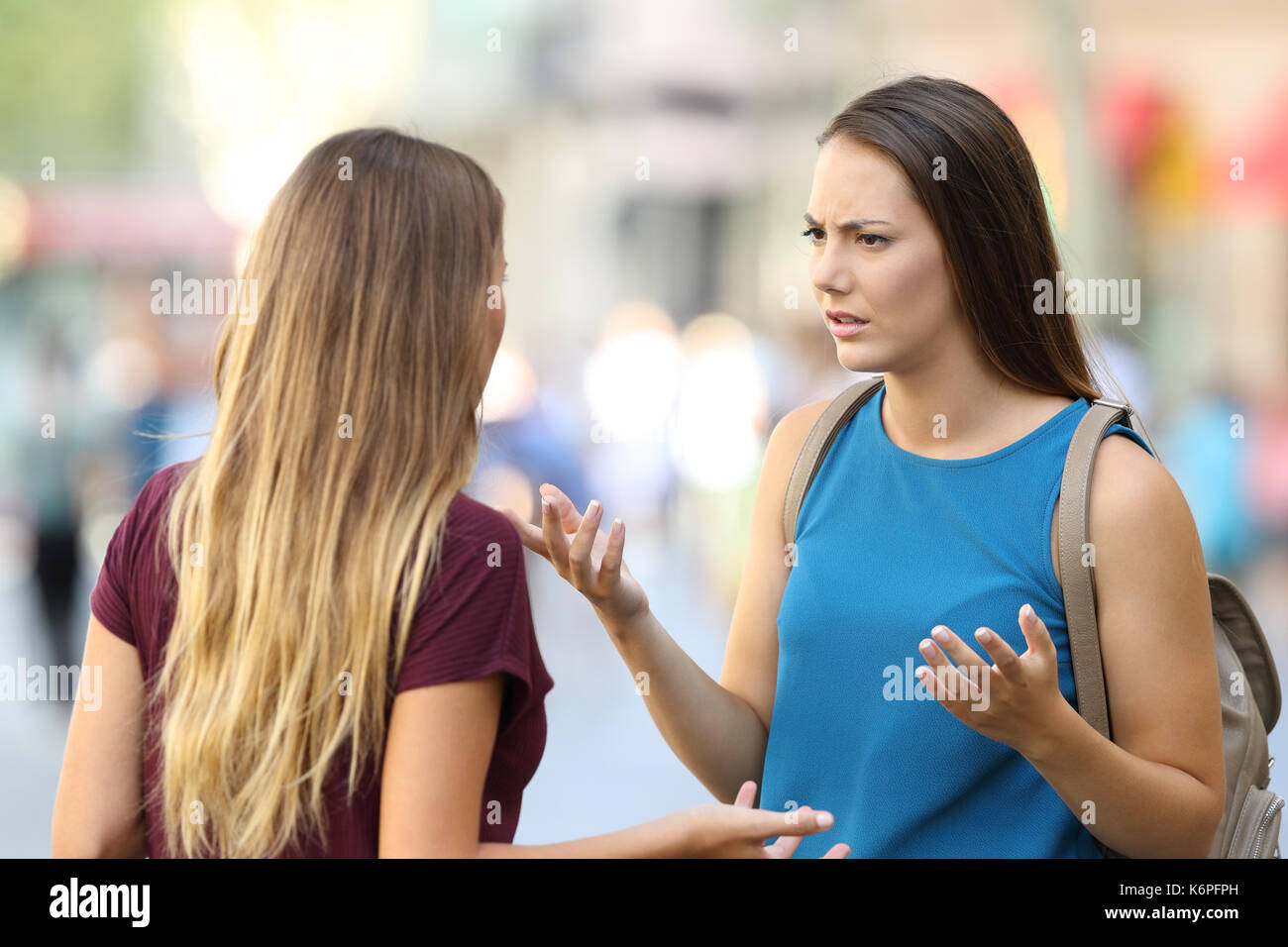 Two angry women friends talking seriously on the street Stock Photo