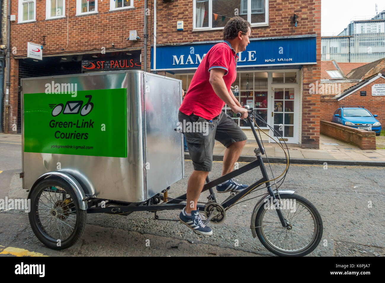 Green Link cycle courier on a tricycle with a large storage box for cargo providing a local emission free delivery in York Stock Photo