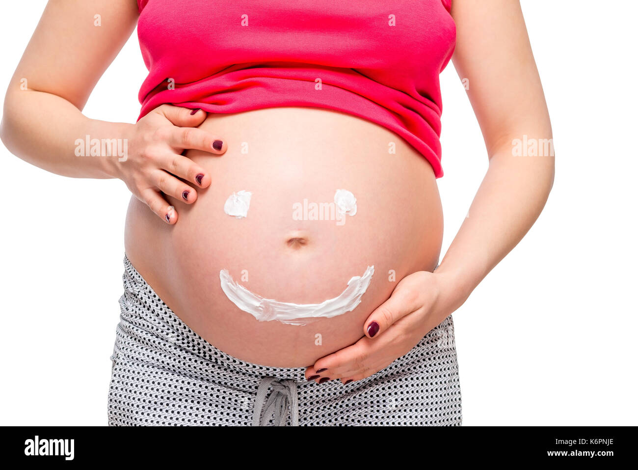 On white background belly of a pregnant woman close-up with a painted smiley Stock Photo