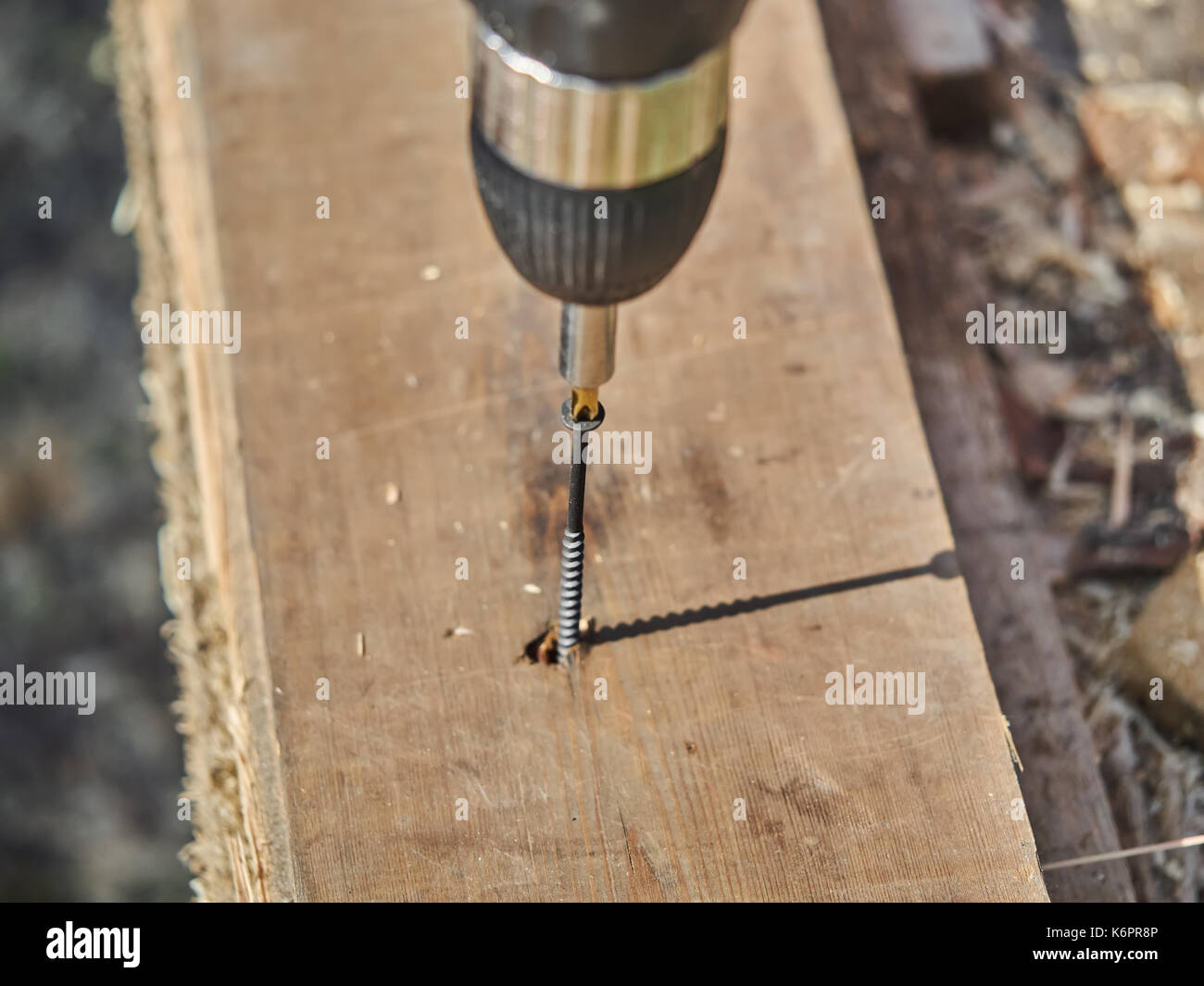 The builder screws the screw into the board Stock Photo