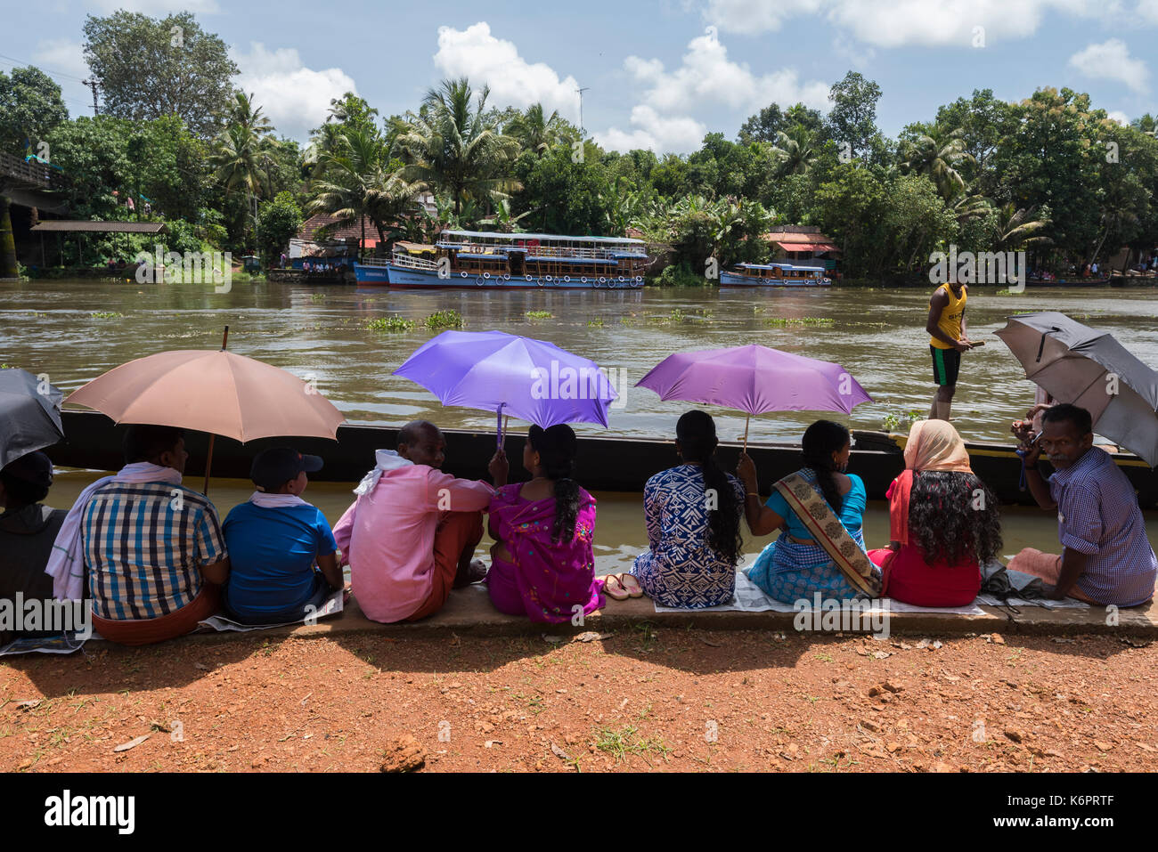 People waiting for the boat race to begin on a very sunny day by taking shade under their umbrellas. Stock Photo