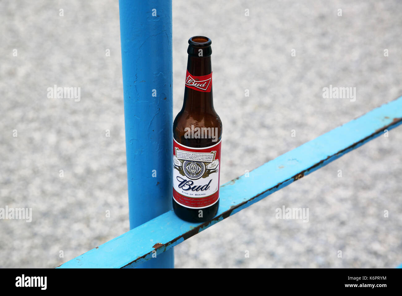 Menton, France - May 14, 2016: Bottle of Budweiser Beer on a Blue Metal Fence, Beach in the Background Stock Photo