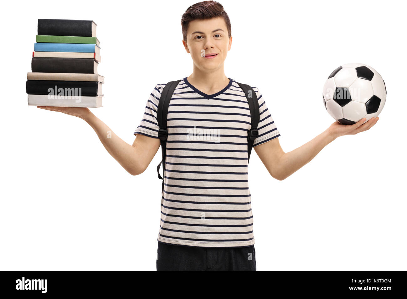 Teenage student holding a stack of books and a football isolated on white background Stock Photo