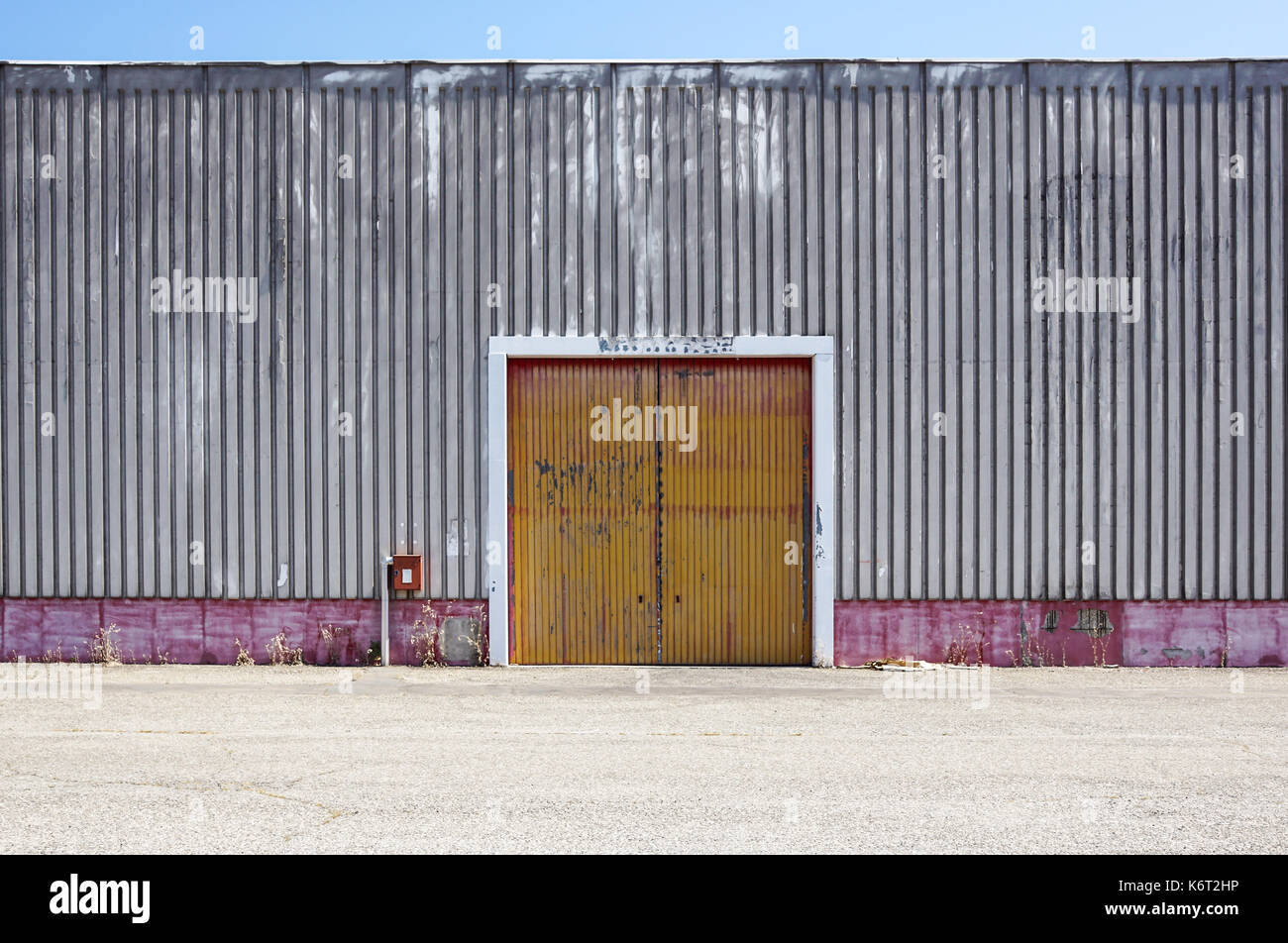 The sheet metal factory wall with the entrance door in the industrial