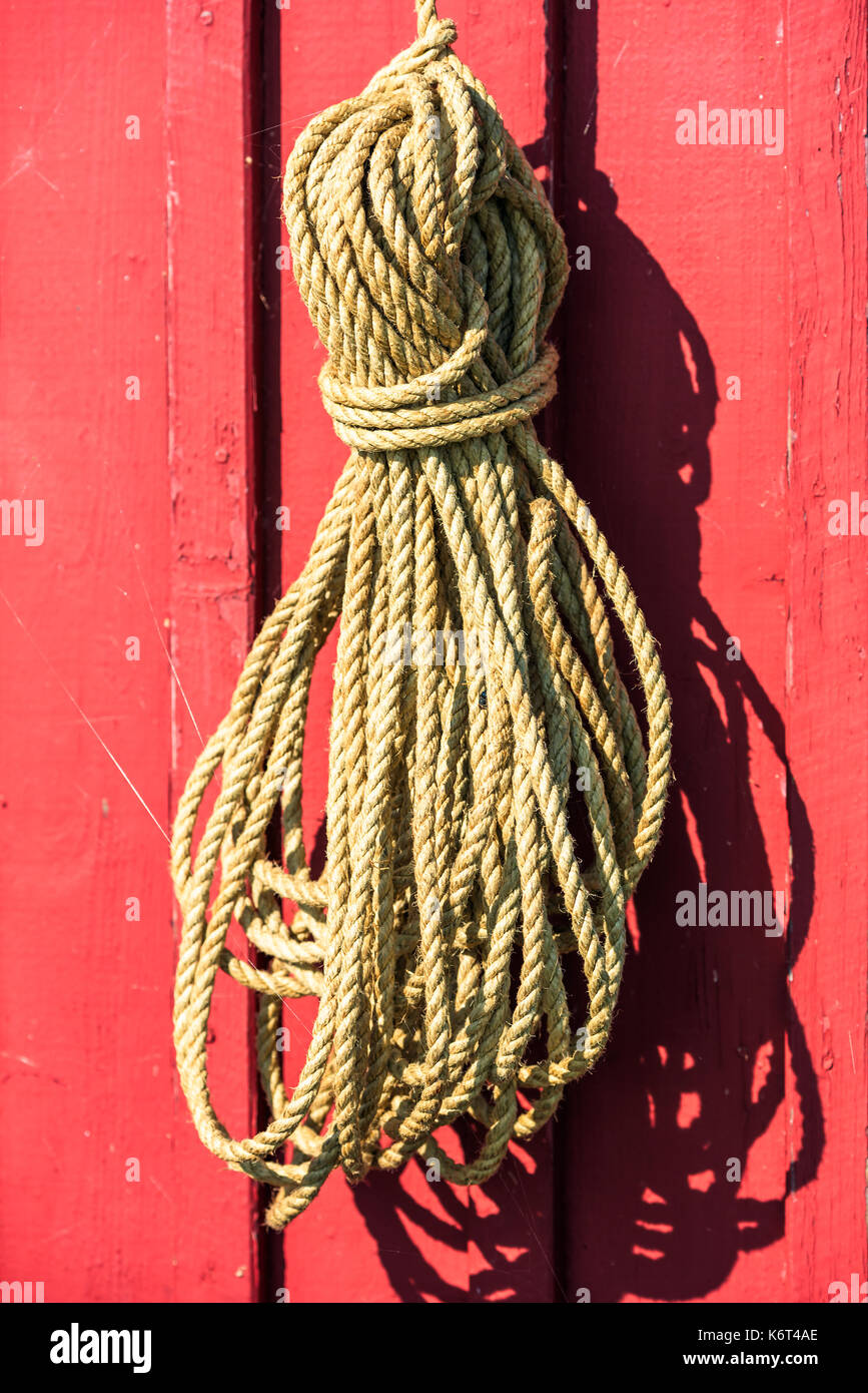 Natural material rope hanging on red wooden wall Stock Photo