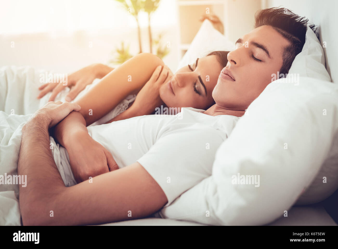 Romantic hugging young couple sleeping in bed Stock Photo - Alamy