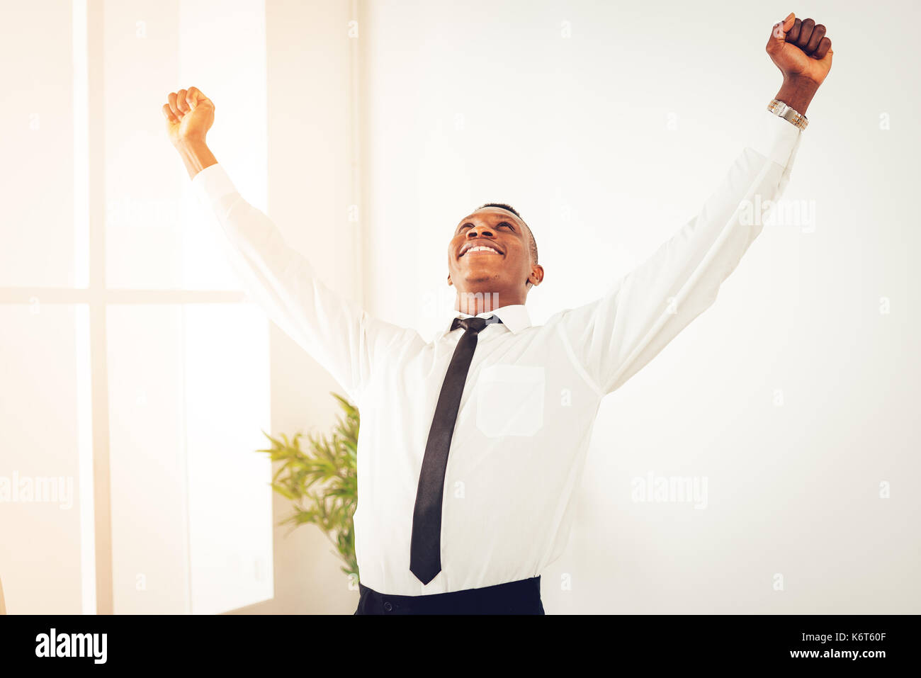 Successful African businessman celebrating success with raised arms in ...