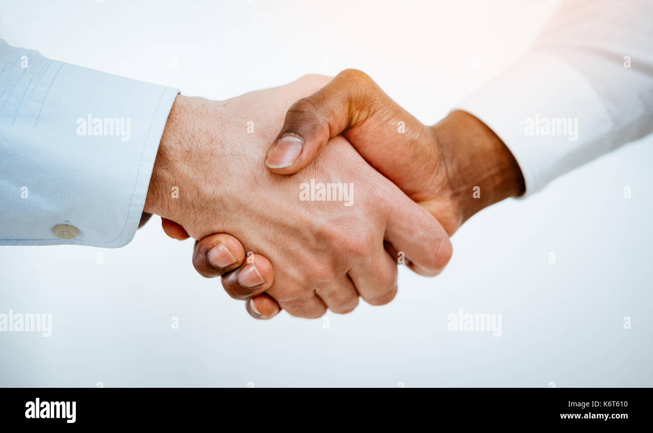 Close-up of a black and white hands shaking over a good business agreement. Stock Photo
