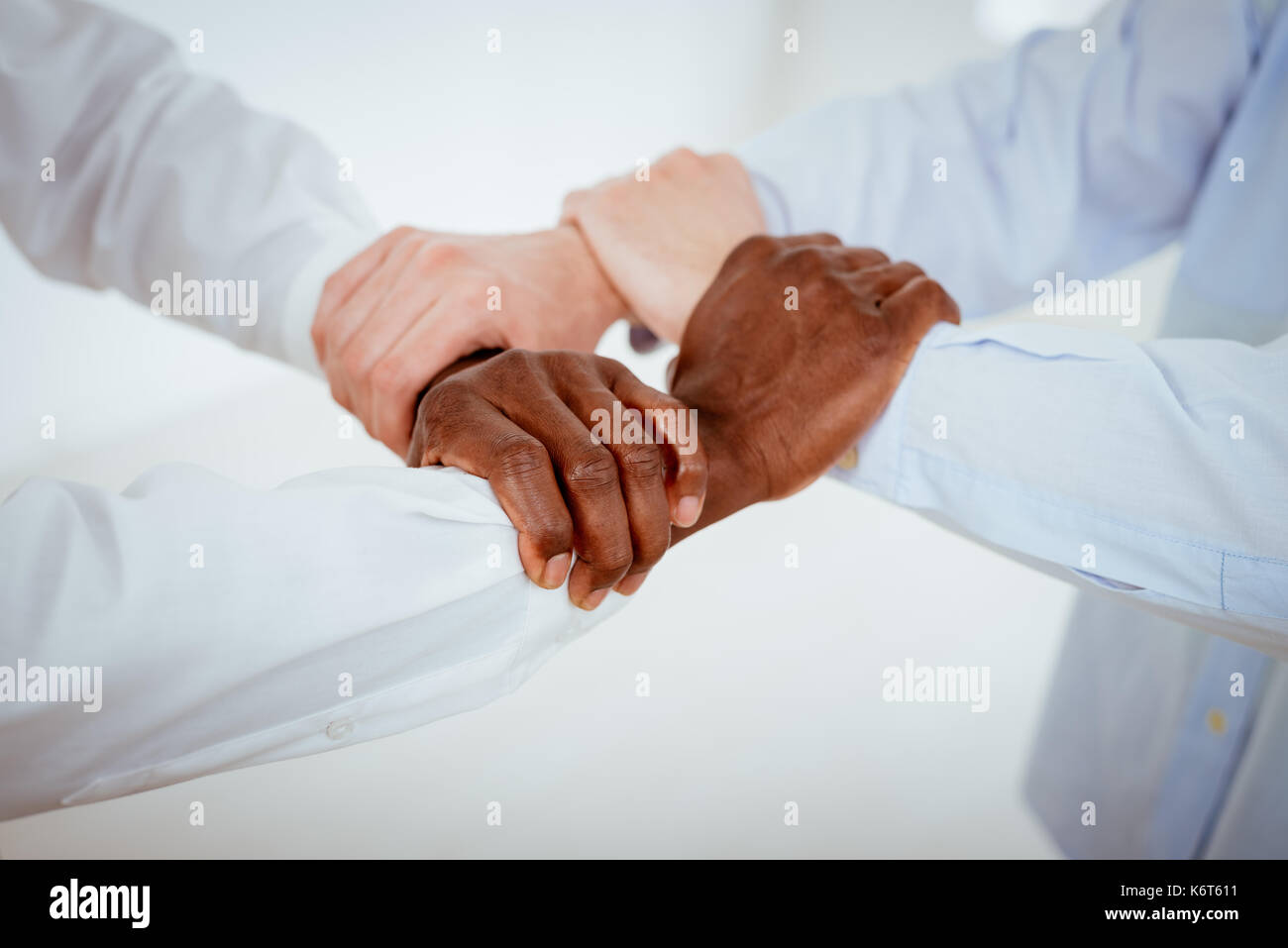 Close-up of a four black and white hands holding together tightly. Stock Photo